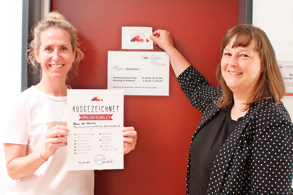 zwei Mitarbieterinnen der AWO Schwaben halten Urkunde mit Auszeichnung "familienfreundliches Augsburg" hoch, lächelnd